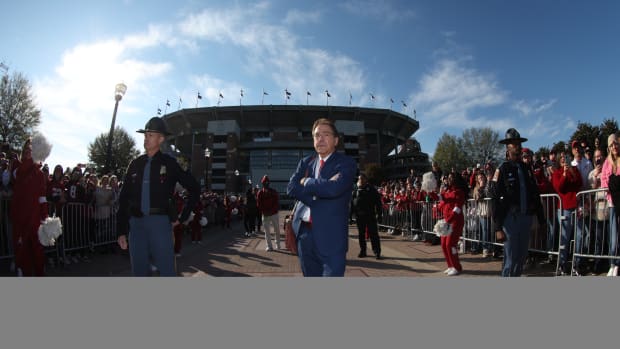 Nick Saban with arms cross in front of Bryant-Denny Stadium